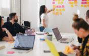 Young people brainstorming around a table with post-its on the wall. Credit: You X Ventures, Unsplash