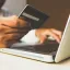 A person holding a credit card and working on a laptop. Credit: Rupixen Com, Unsplash